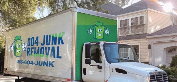 A white truck with "GO4 Junk Removal" and a cartoon green trash can logo parked on a residential street. Contact number 866-GO4-JUNK is displayed on the side.